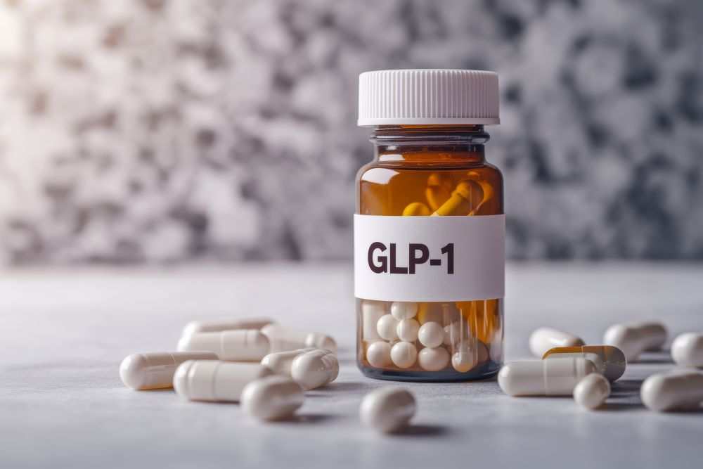 Amber pill bottle labeled GLP-1 with white capsules and round tablets scattered around on a table